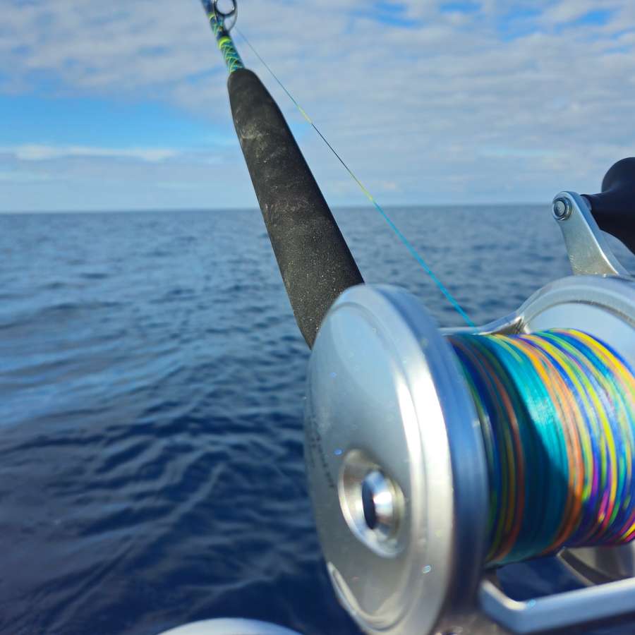 Mulinello con il trecciato colorato e canna in curva sul mare