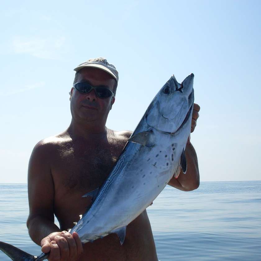 Il pescatore con una cattura tra le mani, sul mare piatto