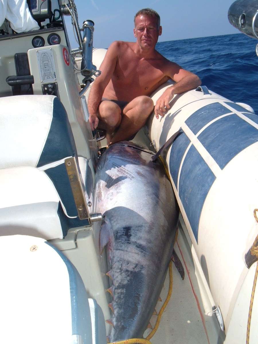 Il pescatore seduto sul tubolare del gommone, con una grossa cattura sul ponte