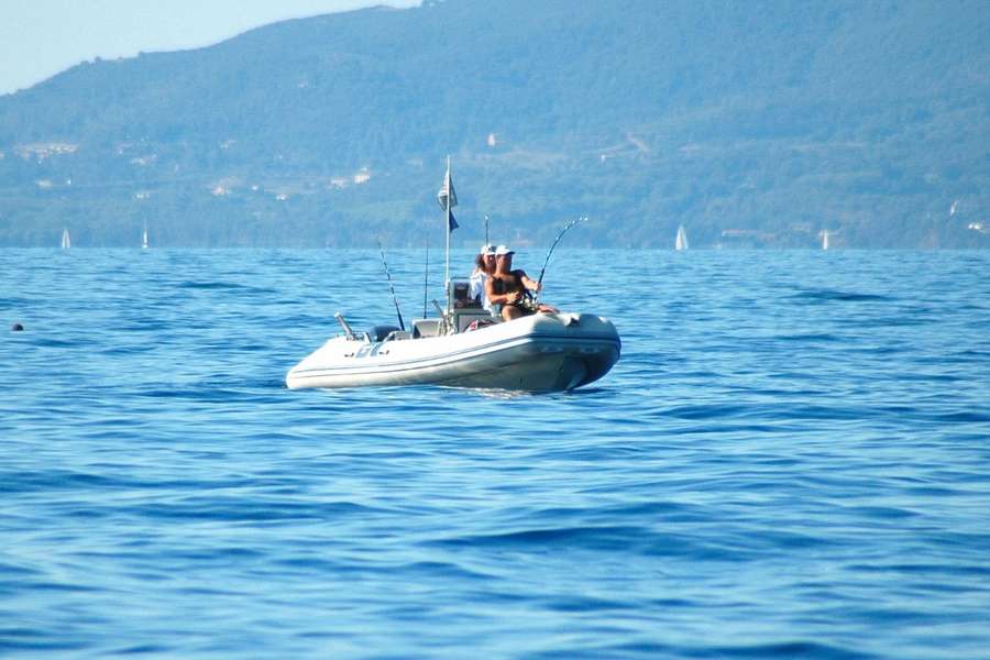 Un gommone in pesca sotto costa, con le colline dietro