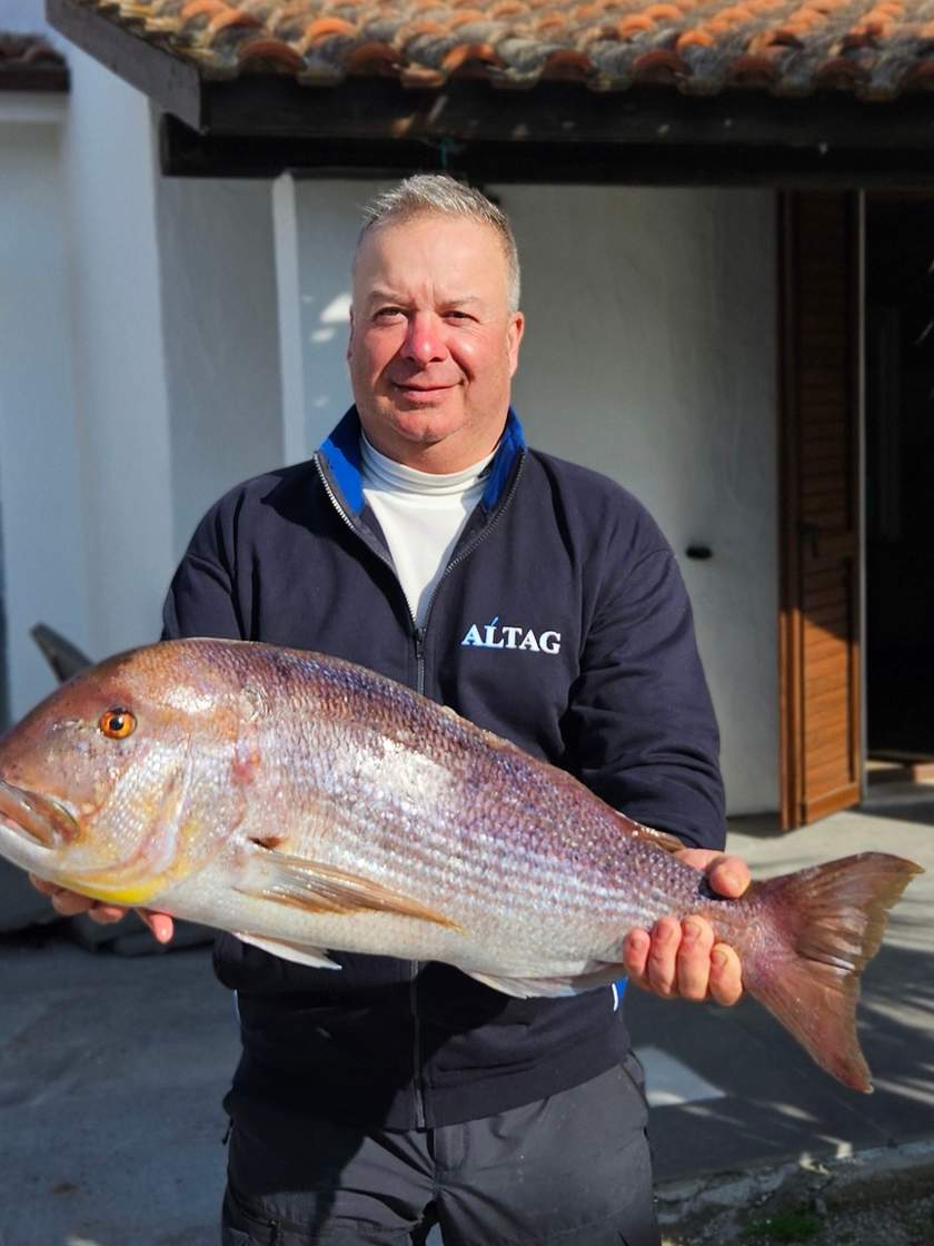 La guida di pesca sorridente con una grossa cattura tra le mani, davanti a casa