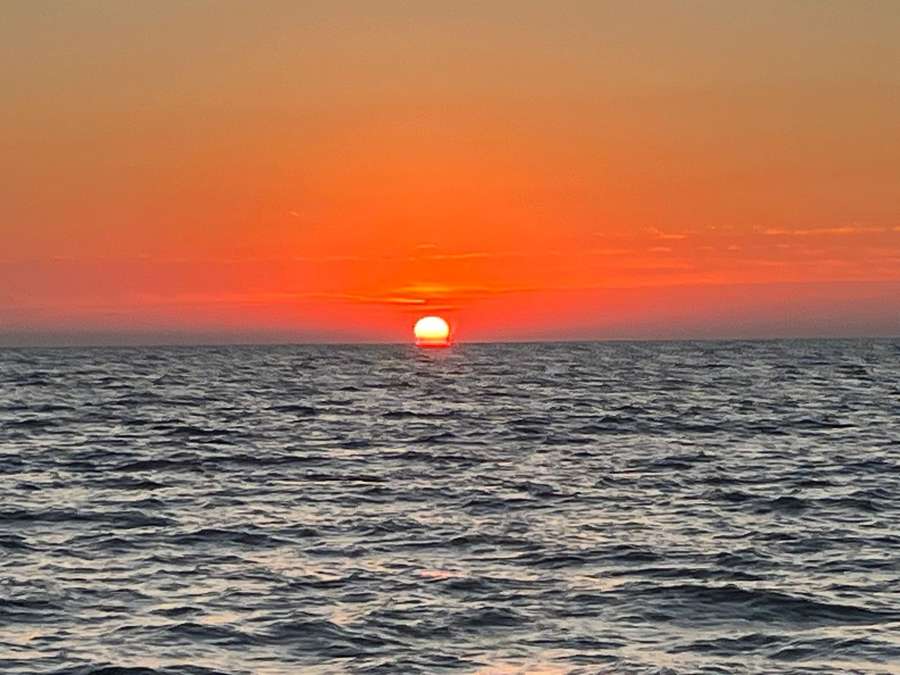 Il sole basso sull’orizzonte, cielo arancio e mare increspato