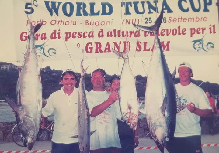 Stampa di una foto d’epoca: tre pescatori con le catture appese sotto lo striscione del Grand Slam a Porto Ottiolu